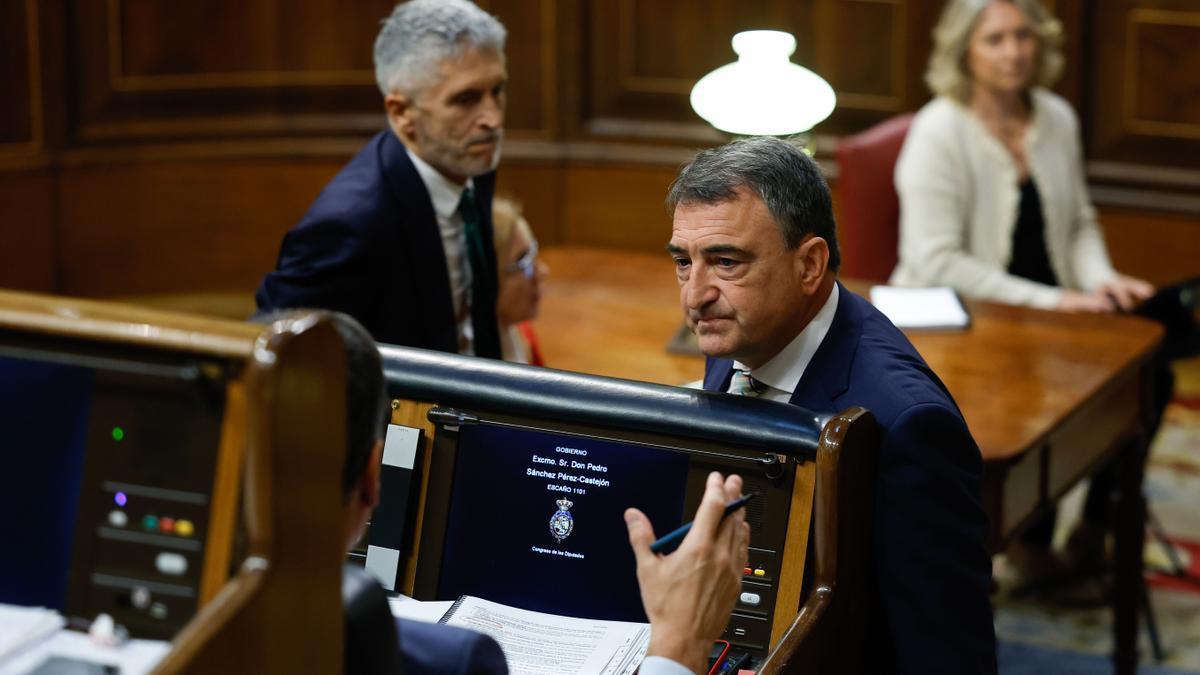 El portavoz del PNV en el Congreso, Aitor Esteban, conversa con el presidente del Gobierno español, Pedro Sánchez, de espaldas en su escaño