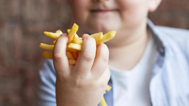 Un niño muestra unas patatas fritas.