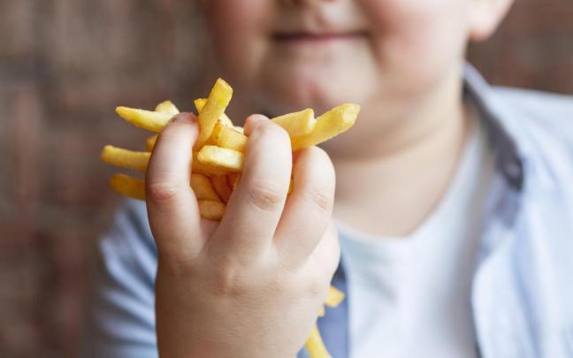 Un niño muestra unas patatas fritas.