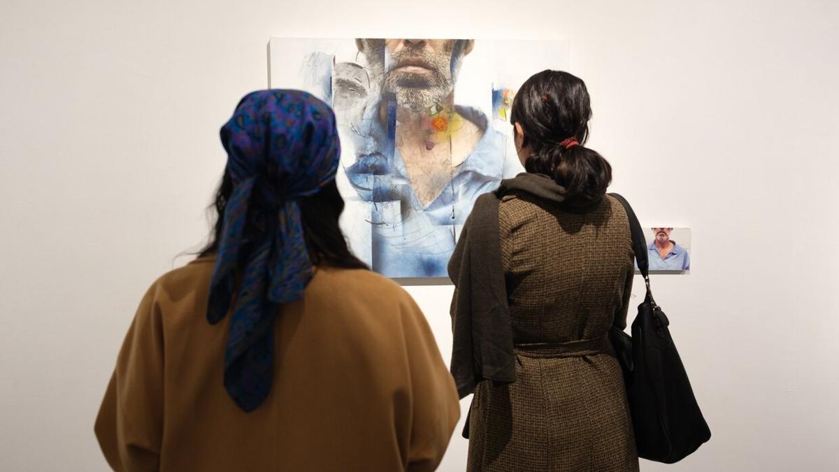 Dos mujeres observan una de las imágenes de la exposición 'Nº7, a la vera del río' en la galería Hoor Art de Teherán