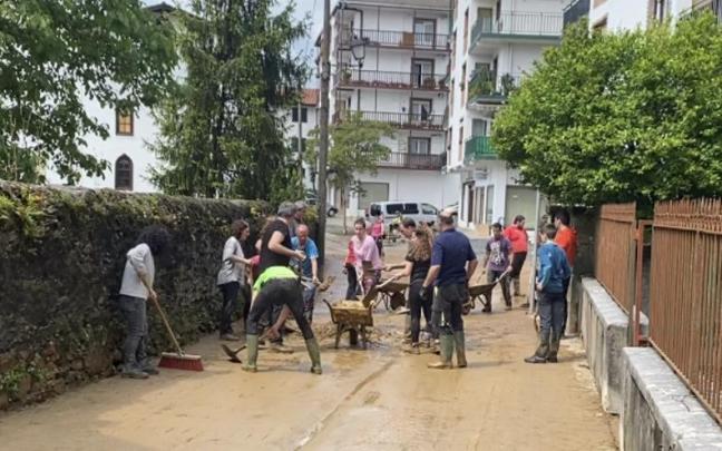 Vecinas y vecinos de todas las edades retiran barro de una calle. Vecinas y vecinos de todas las edades retiran barro de una calle.