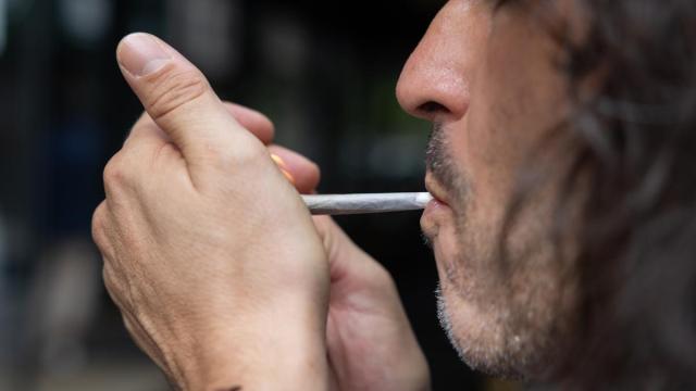 Una persona fuma un cigarro en la calle.