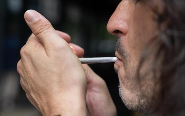 Una persona fuma un cigarro en la calle.
