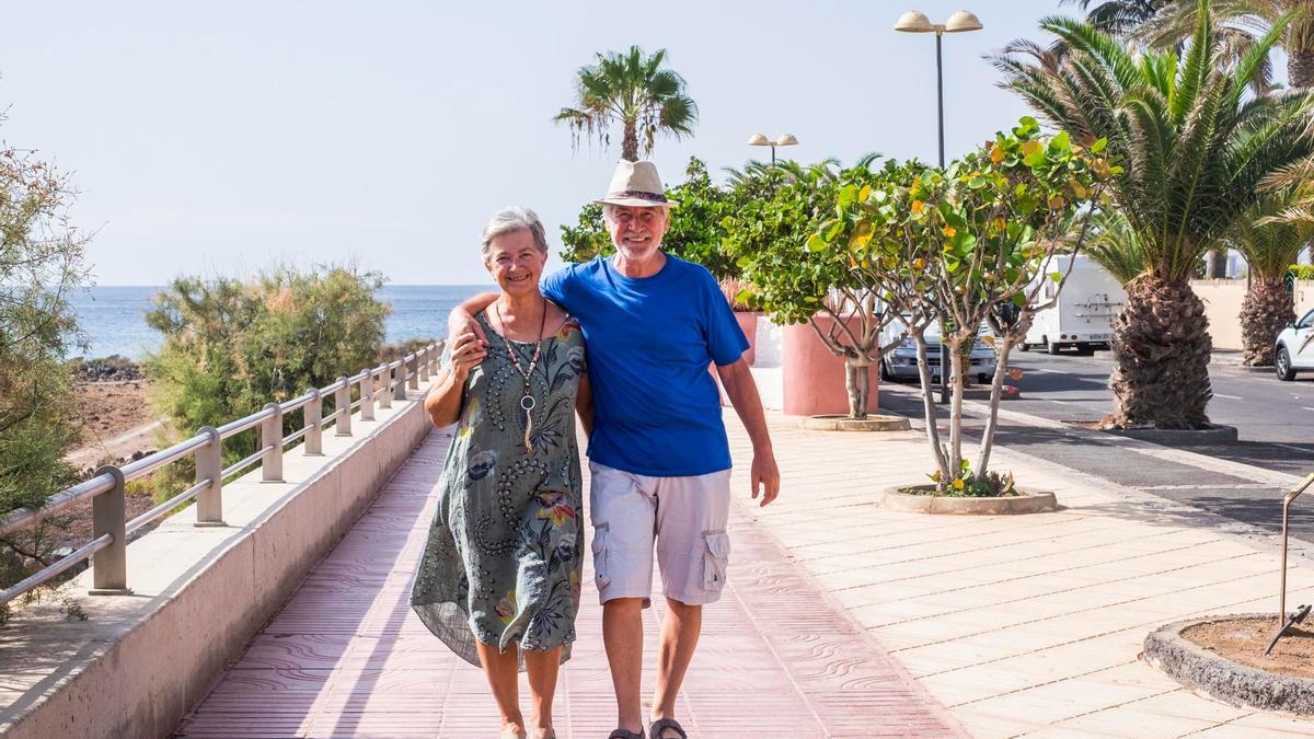 Una pareja mayor camina por un paseo marítimo.