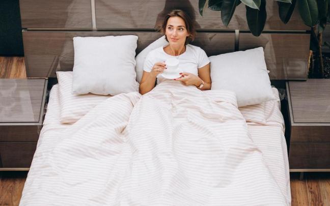 Joven mujer descansando en la cama por la mañana
