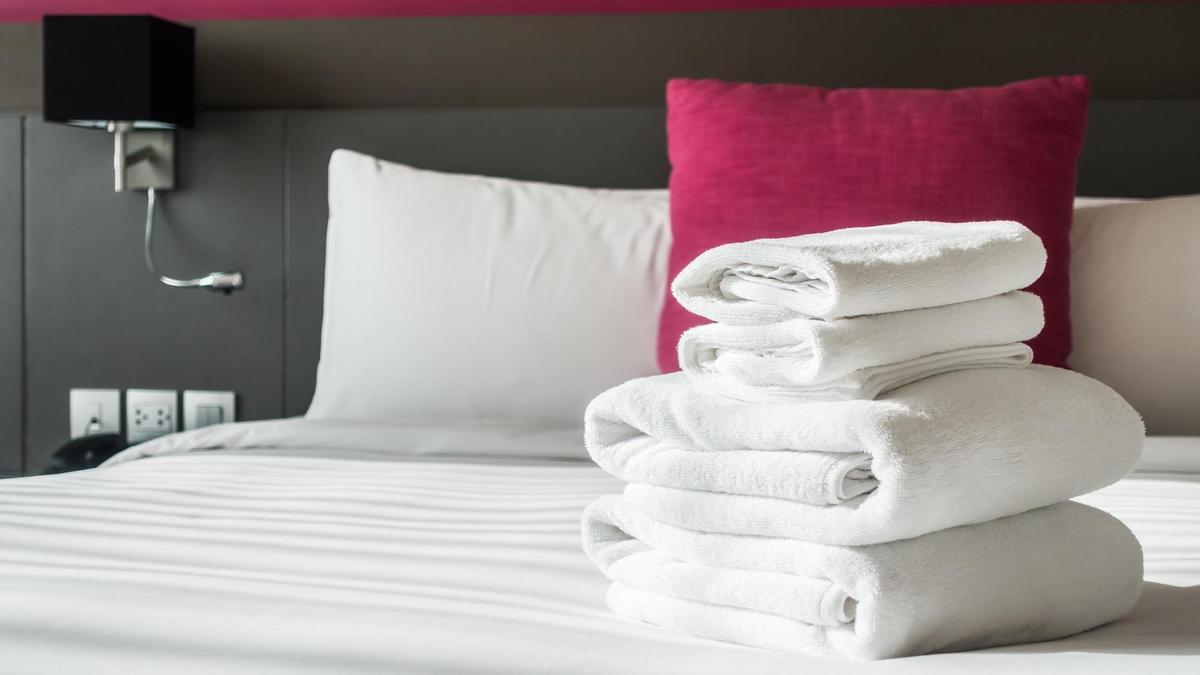 Toallas blancas dobladas sobre la cama de un hotel.