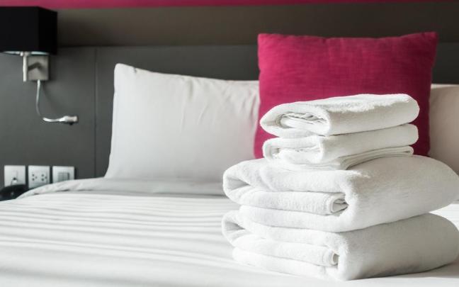 Toallas blancas dobladas sobre la cama de un hotel.