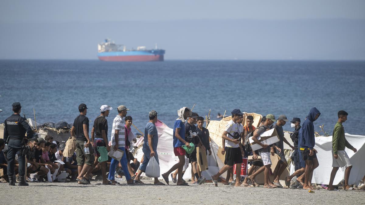 Decenas de migrantes caminan por la playa del Trampolín.