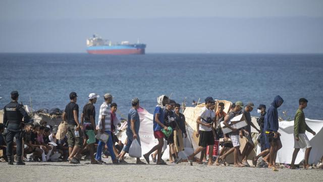Decenas de migrantes caminan por la playa del Trampolín.