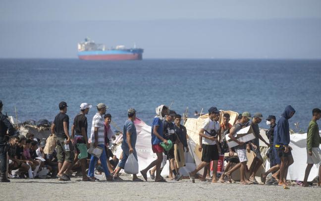 Decenas de migrantes caminan por la playa del Trampolín.
