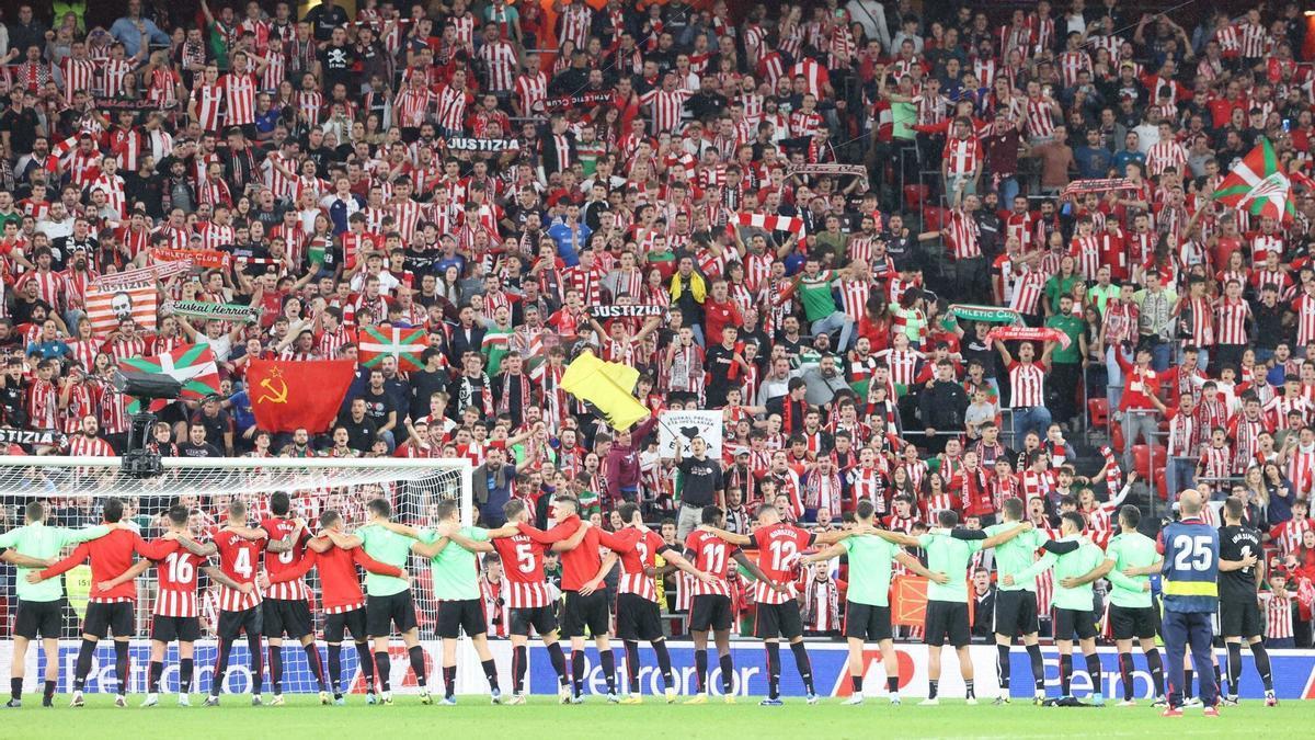 Los jugadores del Athletic se reúnen sobre el césped mientras el público jalea desde la grada de San Mamés.