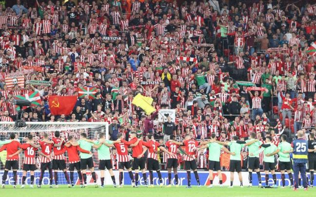 Los jugadores del Athletic se reúnen sobre el césped mientras el público jalea desde la grada de San Mamés.