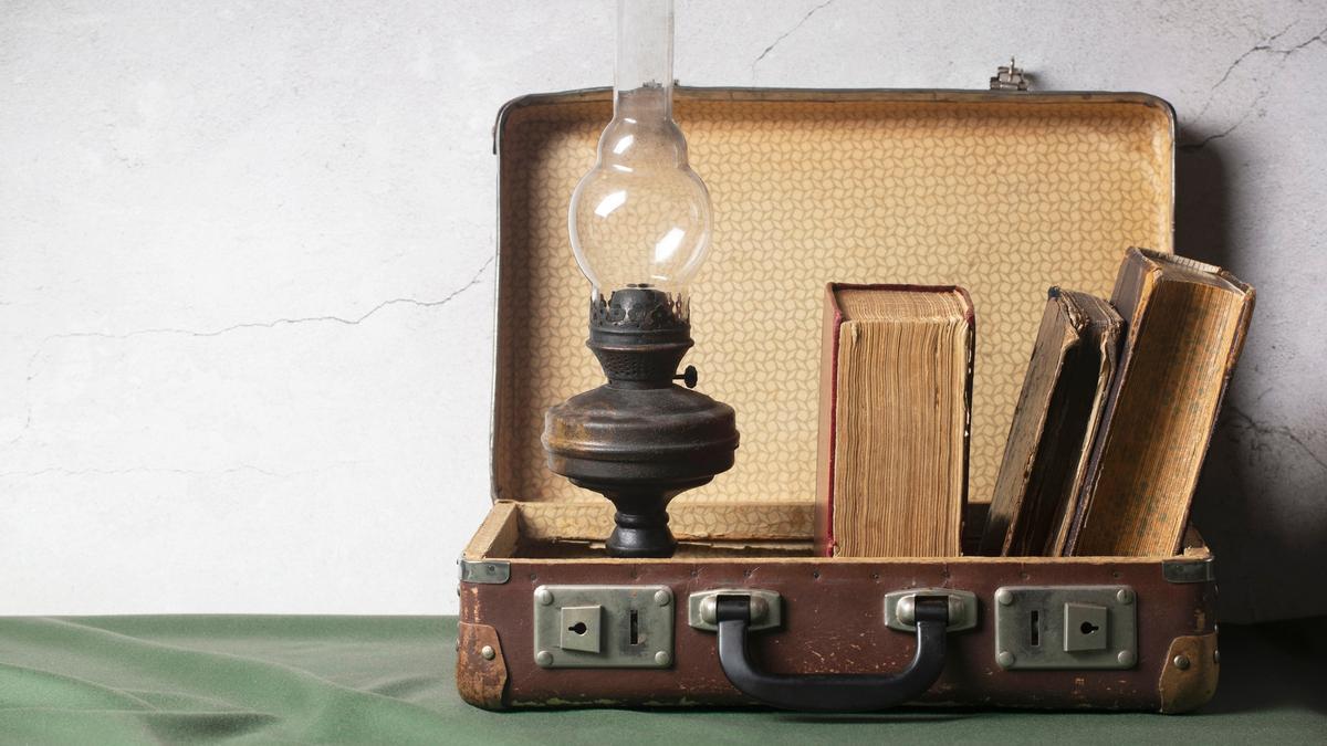 Un maletín vintage como objeto decorativo con libros antiguos y una lámpara.