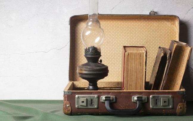 Un maletín vintage como objeto decorativo con libros antiguos y una lámpara.
