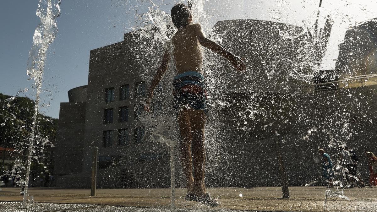 Un joven se refresca en Bilbao durante la ola de calor.
