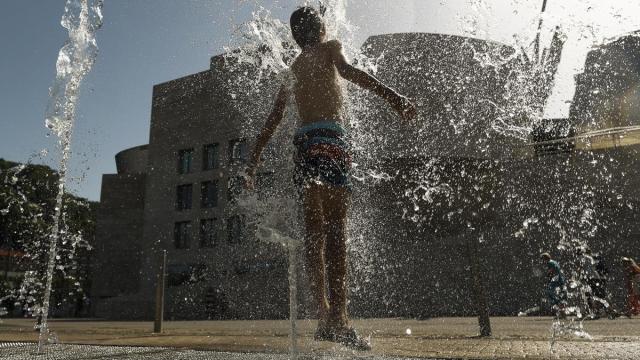 Un joven se refresca en Bilbao durante la ola de calor.