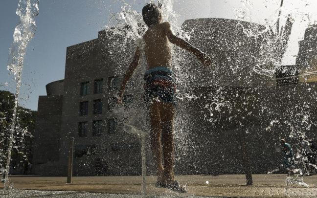Un joven se refresca en Bilbao durante la ola de calor.