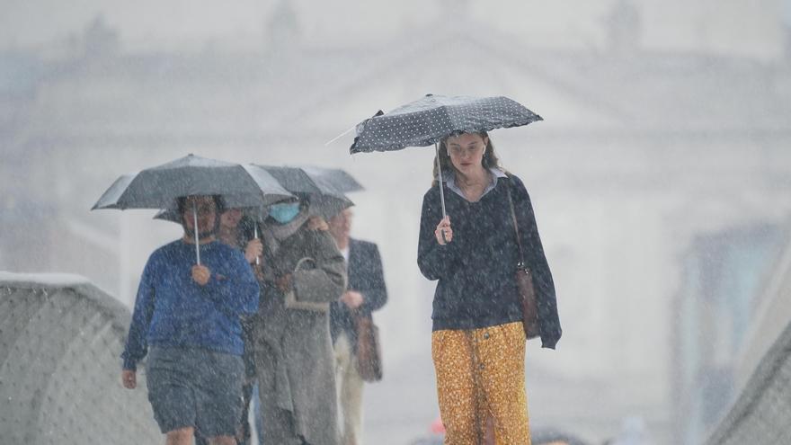 Varias personas se refugian de una fuerte tormenta bajo sus paraguas.