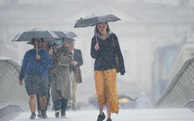 Varias personas se refugian de una fuerte tormenta bajo sus paraguas. / EP Varias personas se refugian de una fuerte tormenta bajo sus paraguas.