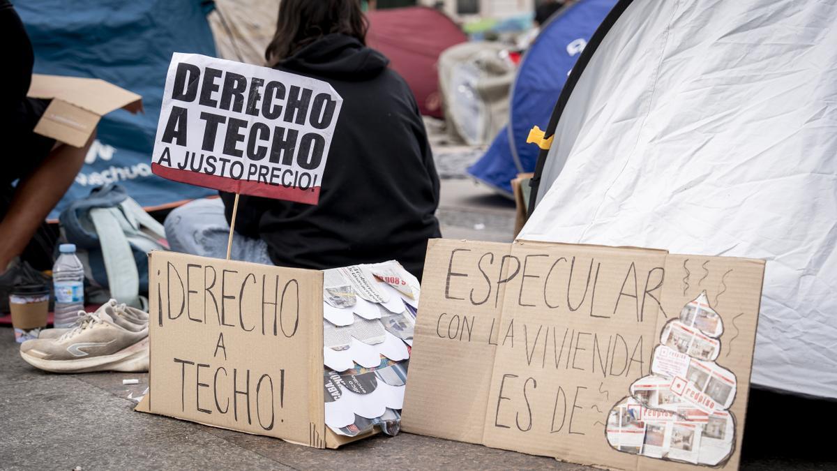 Numerosas personas con pancartas con lemas 'Derecho a techo' se concentran en tiendas de campaña para exigir la aprobación de un decreto sobre vivienda.