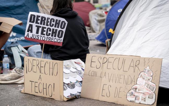 Numerosas personas con pancartas con lemas 'Derecho a techo' se concentran en tiendas de campaña para exigir la aprobación de un decreto sobre vivienda.