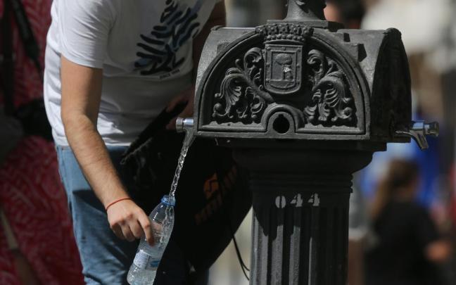 Una persona coge agua de una fuente.