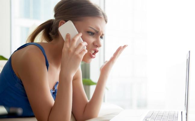 Una mujer atiende enfadada a una llamada comercial desde su móvil.