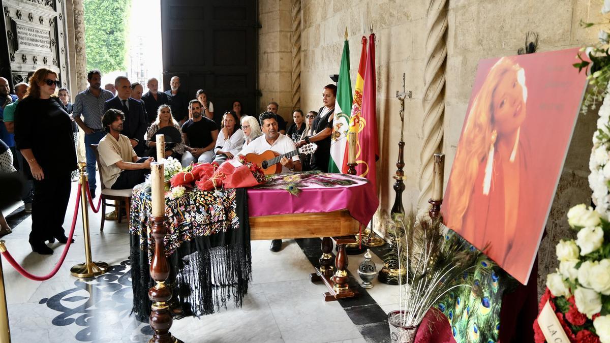 Un hombre, guitarra en mano, canta a la artista María Jiménez en la Capilla Ardiente instalada en el Ayuntamiento de Sevilla.