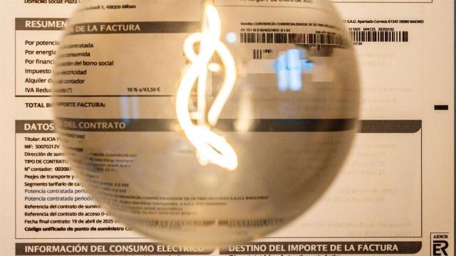 Una bombilla encendida frente a una factura de luz.