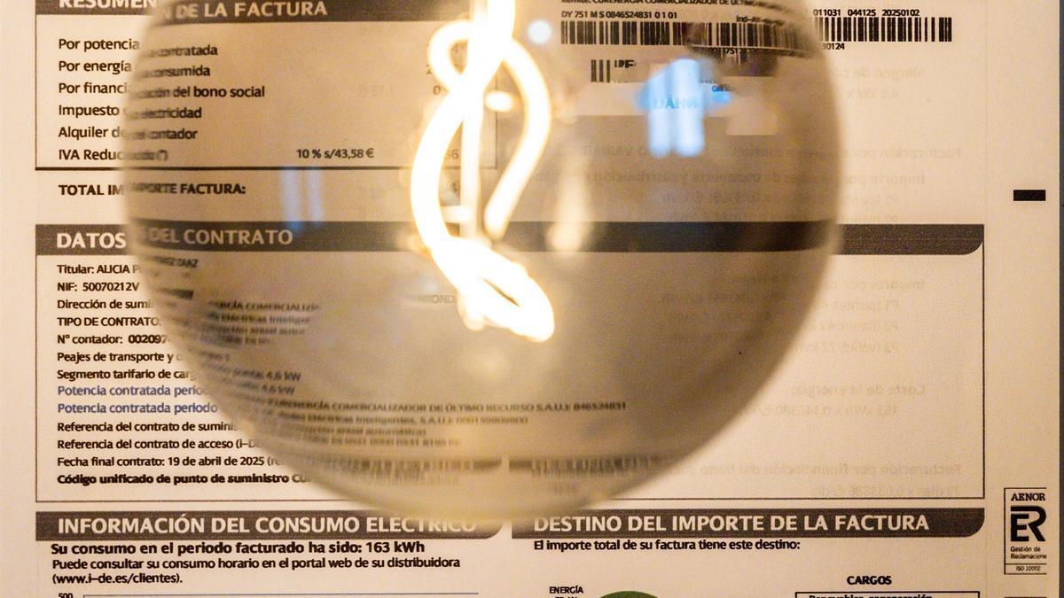 Una bombilla encendida frente a una factura de luz.