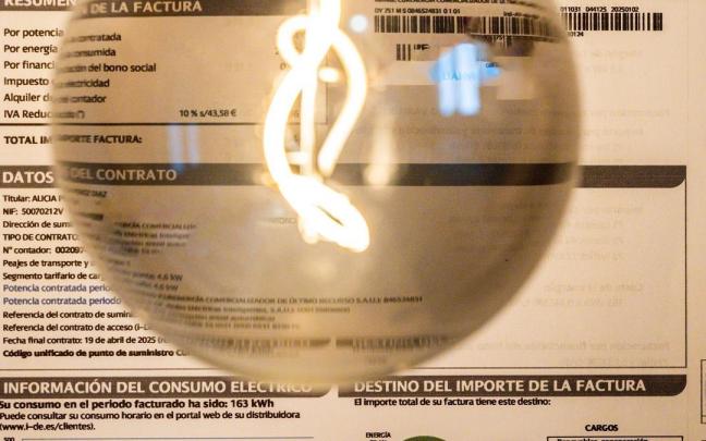 Una bombilla encendida frente a una factura de luz.