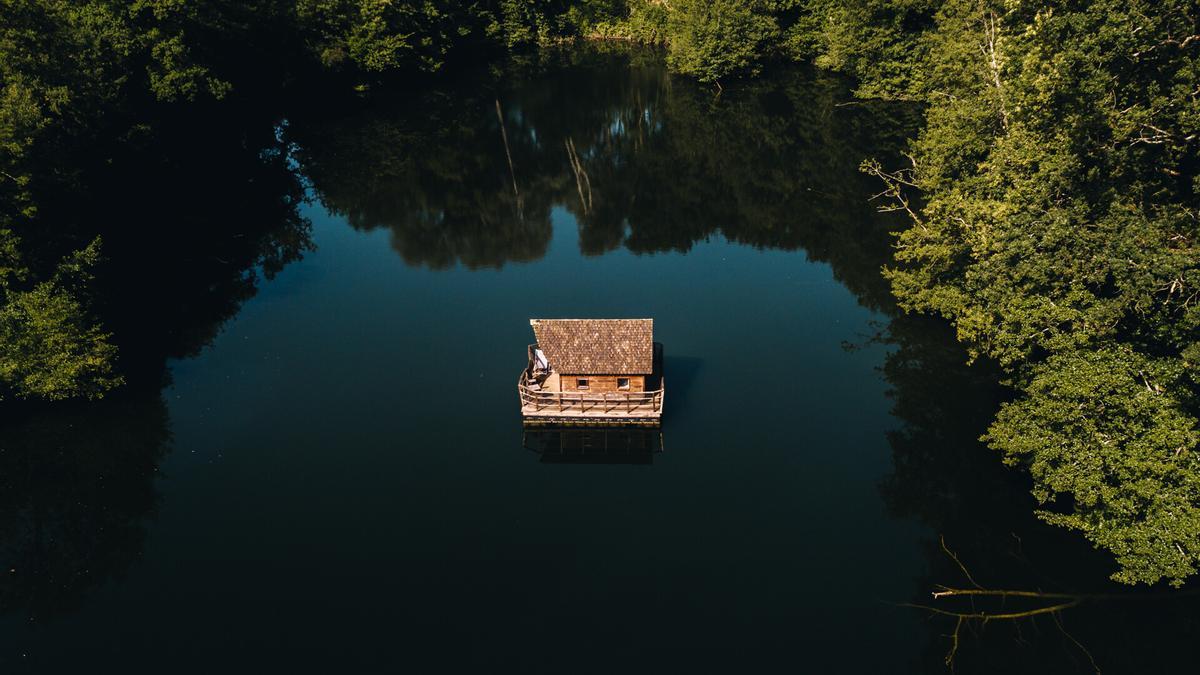 Foto aérea del lago con la cabaña en medio.