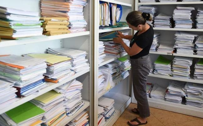 Una mujer, ajena a esta información, revisando expedientes guardados en carpetas.