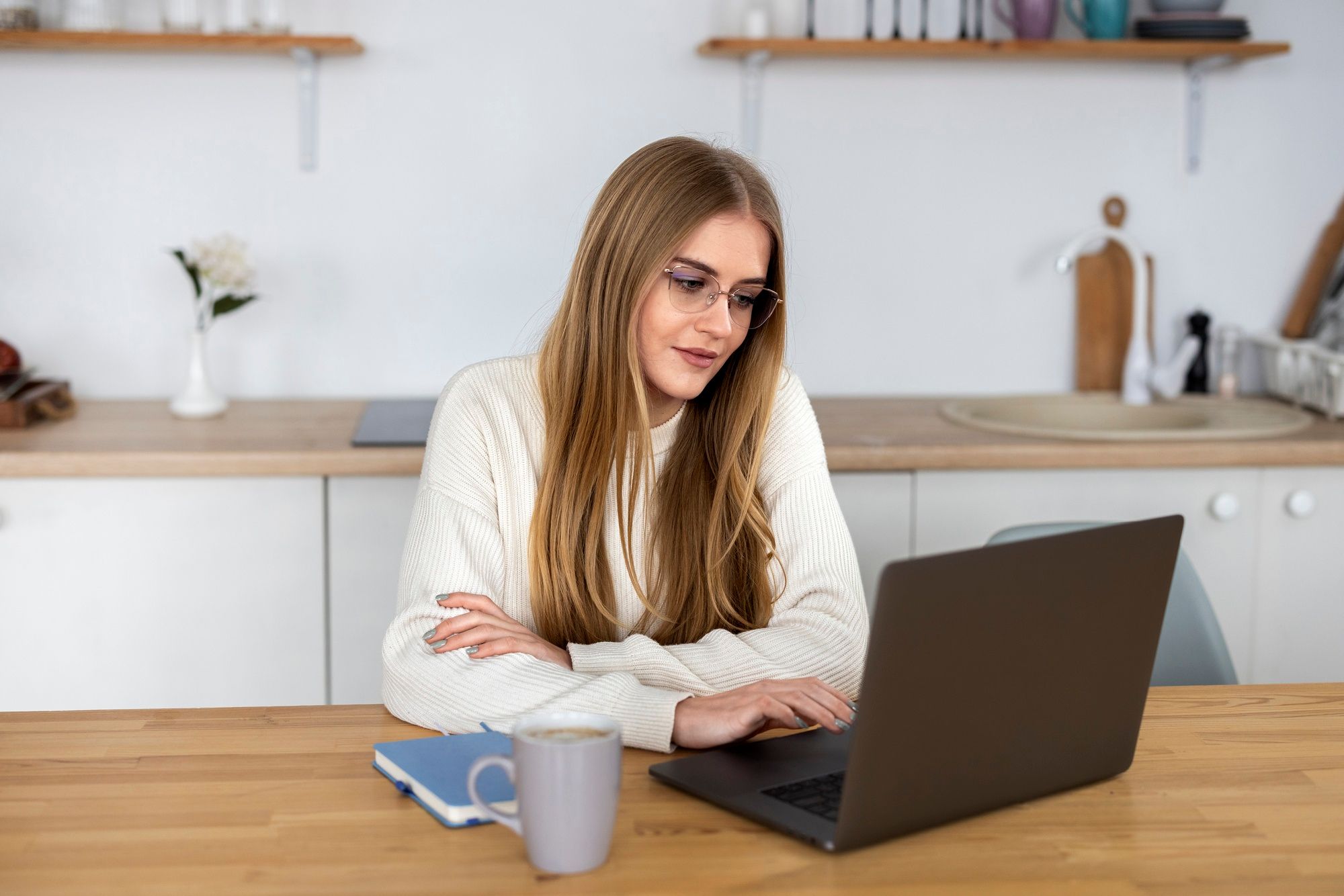 Una chica joven teletrabaja desde la cocina de su casa.