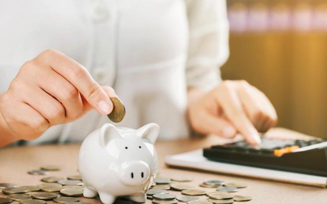 Una persona ahorra metiendo dinero en una hucha tras realizar cálculos financieros. / Freepik Una persona ahorra metiendo dinero en una hucha tras realizar cálculos financieros.