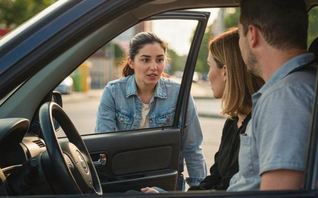 Una pareja pregunta algo desde el coche a una joven.