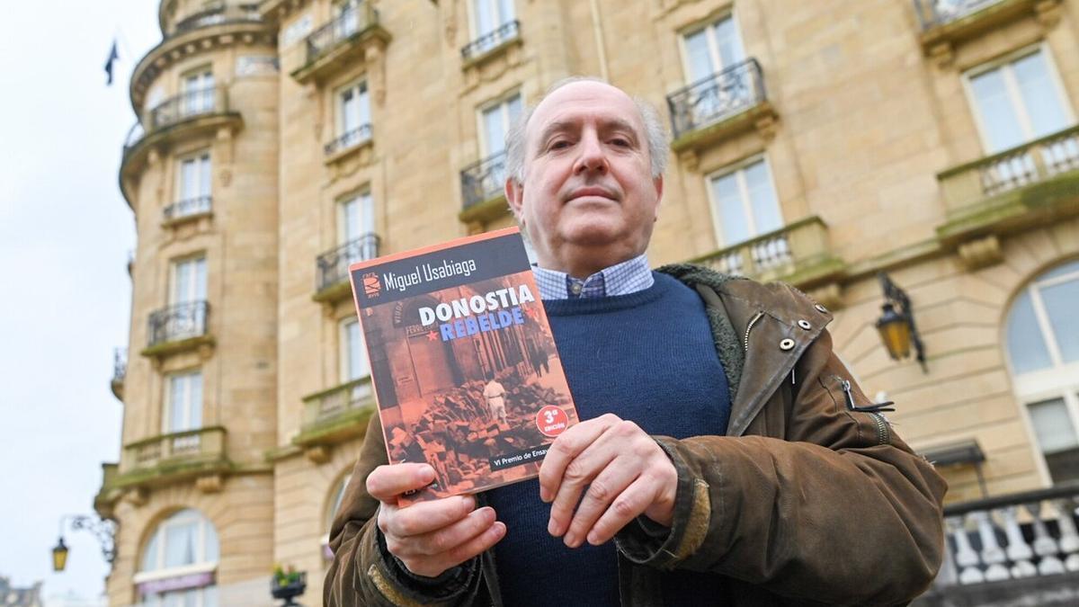 Miguel Usabiaga posa con su libro 'Donostia rebelde' delante del María Cristina.