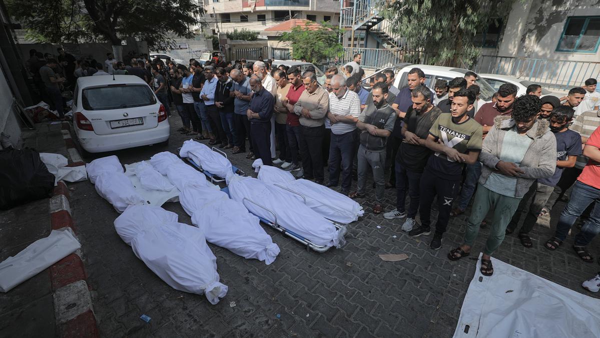 Un grupo de personas reza frente a los cadáveres de seres queridos en Gaza.