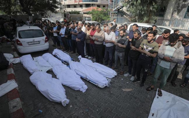 Un grupo de personas reza frente a los cadáveres de seres queridos en Gaza.
