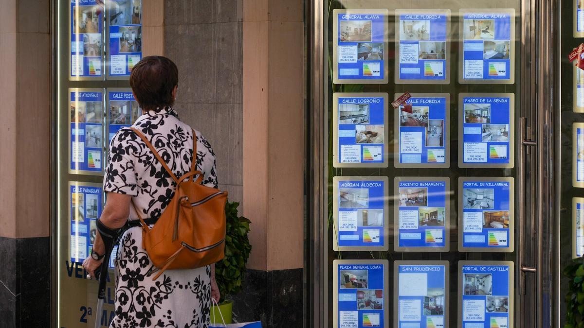 Una persona mirando las ofertas publicadas en el escaparate de una inmobiliaria.