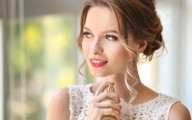 Una mujer sujeta un frasco de perfume.