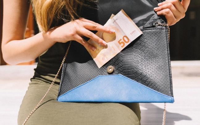 Una mujer saca dinero de la cartera