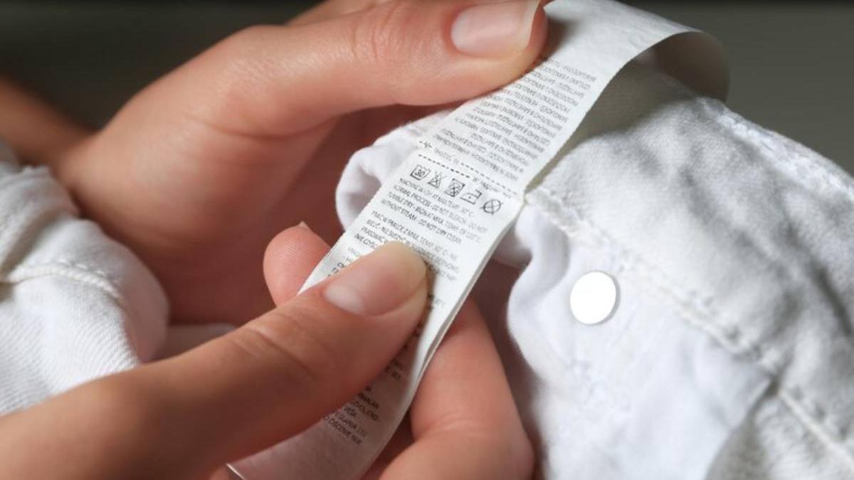 Mujer leyendo la etiqueta de la ropa con instrucciones de cuidado