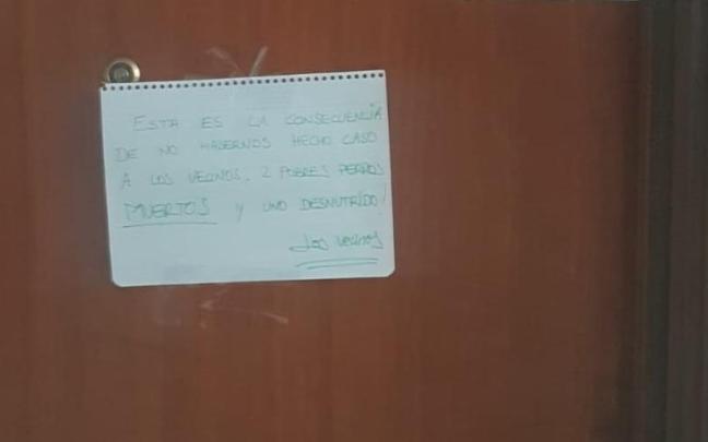 Imagen de la puerta en la que los vecinos de Igorre han colocado el cartel de denuncia por los perros muertos en un piso