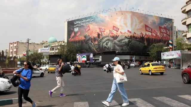 Varios iraníes pasan junto a una valla publicitaria antiestadounidense en Teherán.