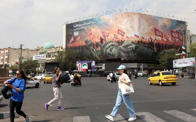 Varios iraníes pasan junto a una valla publicitaria antiestadounidense en Teherán.
