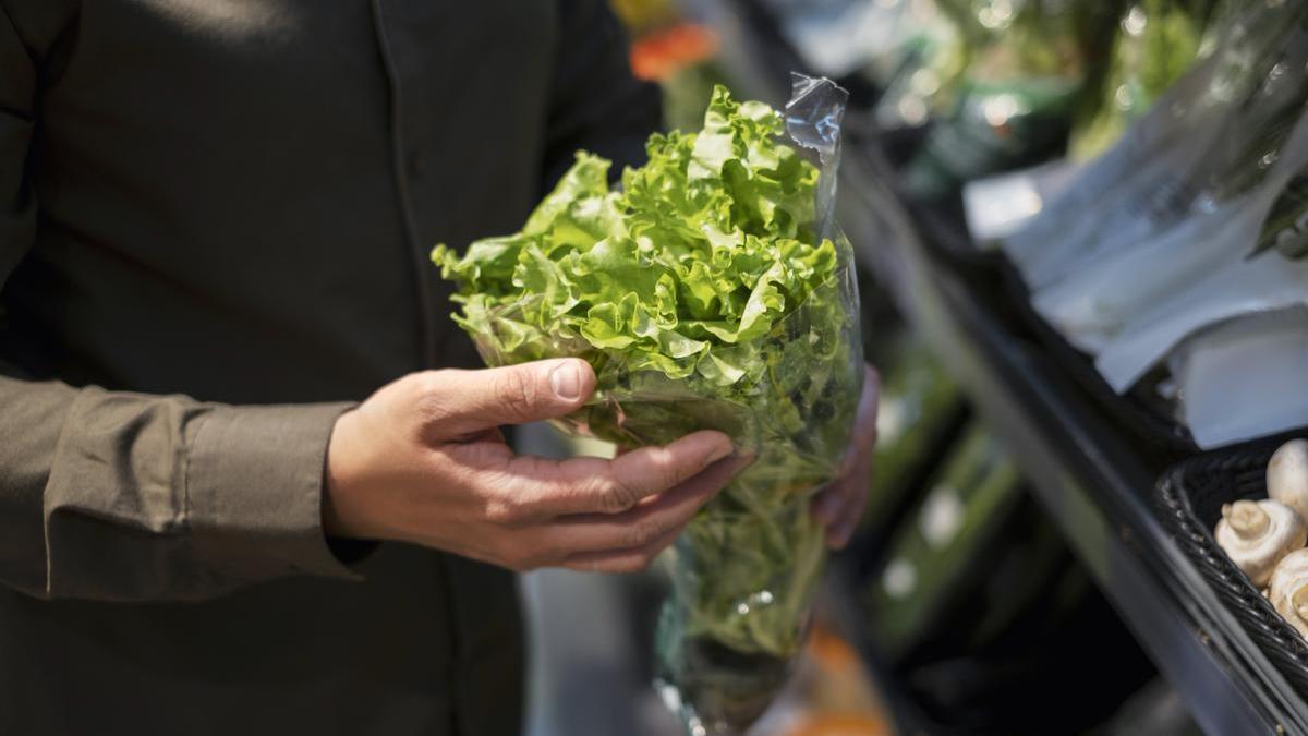 Hombre compra lechuga en el supermercado.