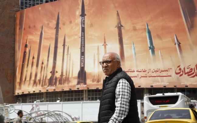 Un hombre pasea en Teherán ante un cartel antiisraelí en el que aparecen imágenes de misiles iraníes.