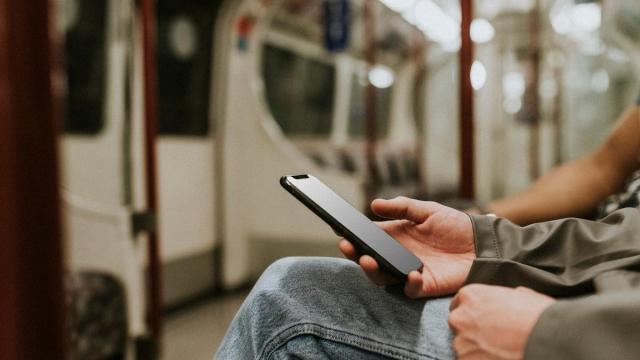 Un usuario del metro sostiene un móvil en la mano. Un usuario del metro sostiene un móvil en la mano.