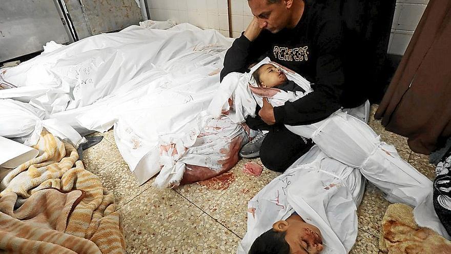 Un hombre sostiene en brazos el cadáver de su hijo muerto en una morgue de un hospital de Gaza. | FOTO: E.P.